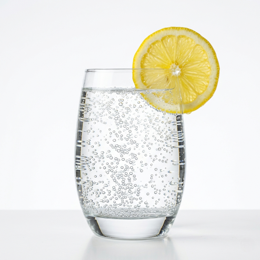 glass of sparkling water with lemon slice and bubbles rising on clean white background representing health and hydration - is sparkling water good for you